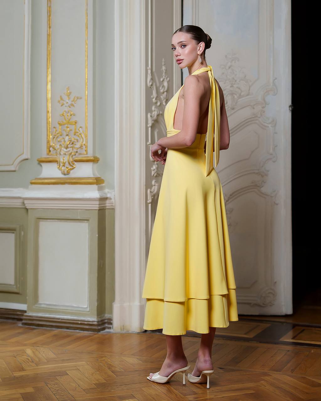 Woman in a yellow dress standing in an elegant interior setting
