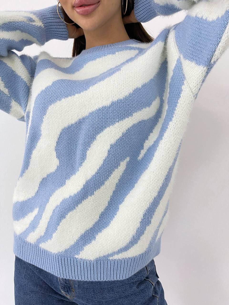 Person wearing a blue and white patterned sweater with a plain background