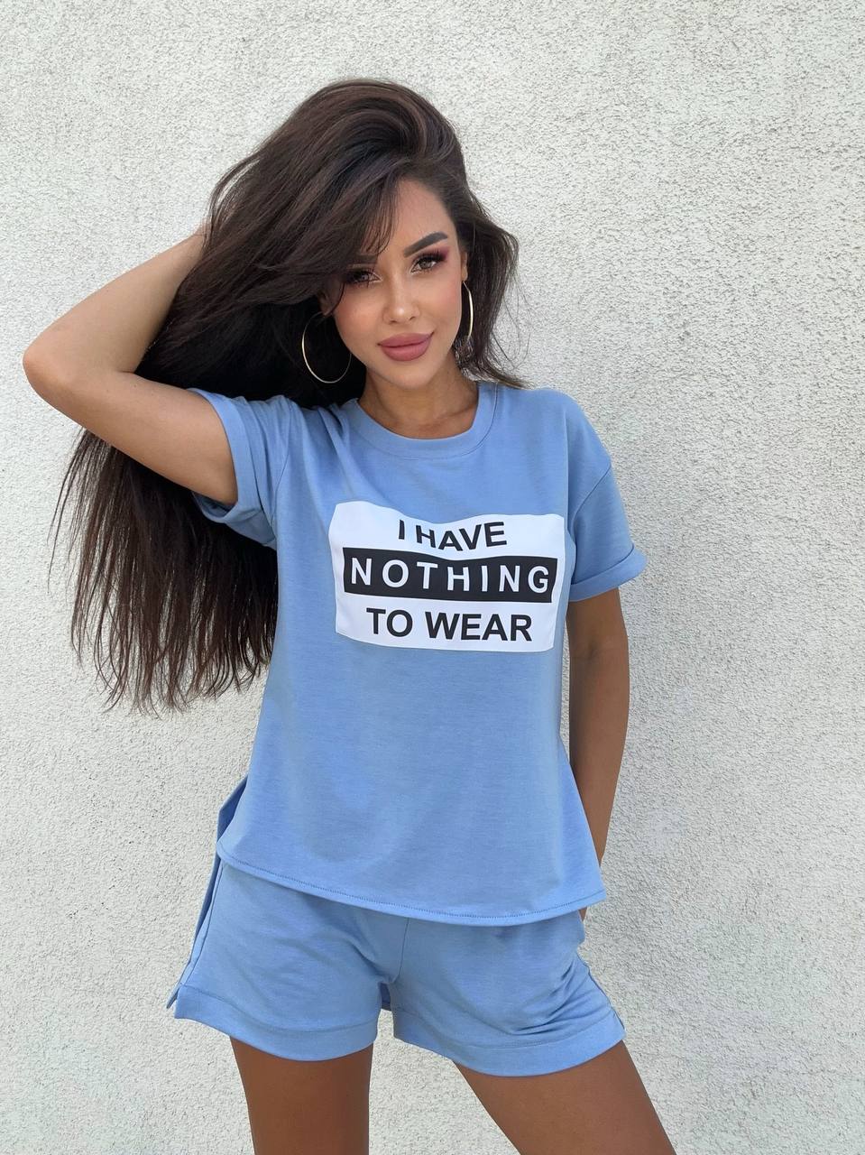 Woman wearing a blue t-shirt with 'I HAVE NOTHING TO WEAR' text against a light gray background