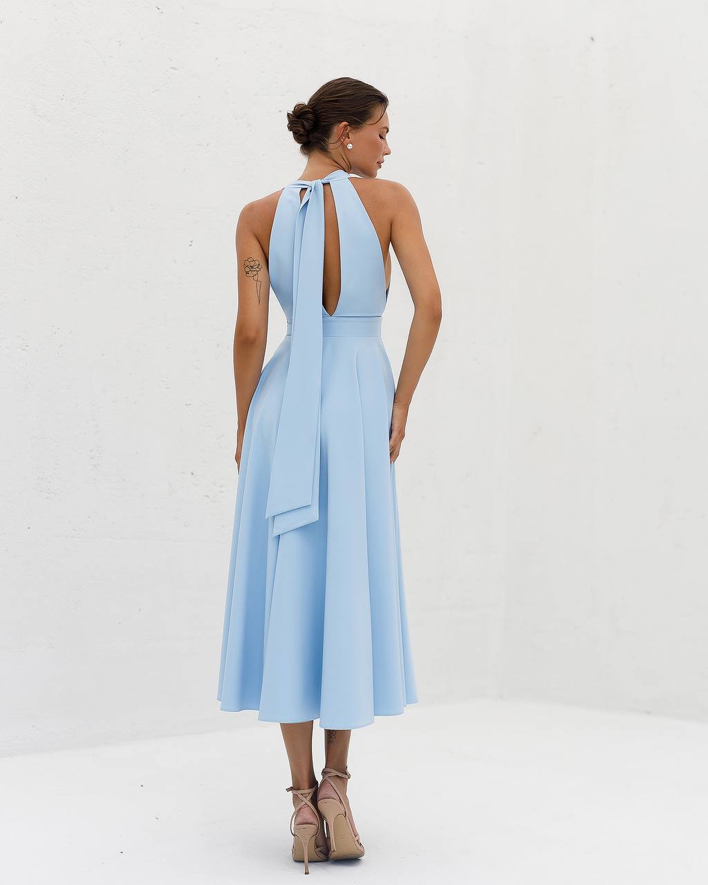 Woman wearing a light blue dress with a halter neck design on a white background