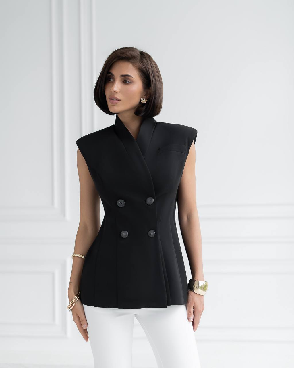 Woman wearing a black sleeveless blazer with a white background