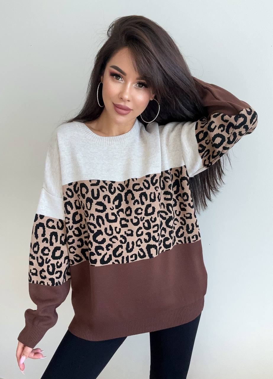 Woman wearing a sweater with leopard print sleeves against a plain background