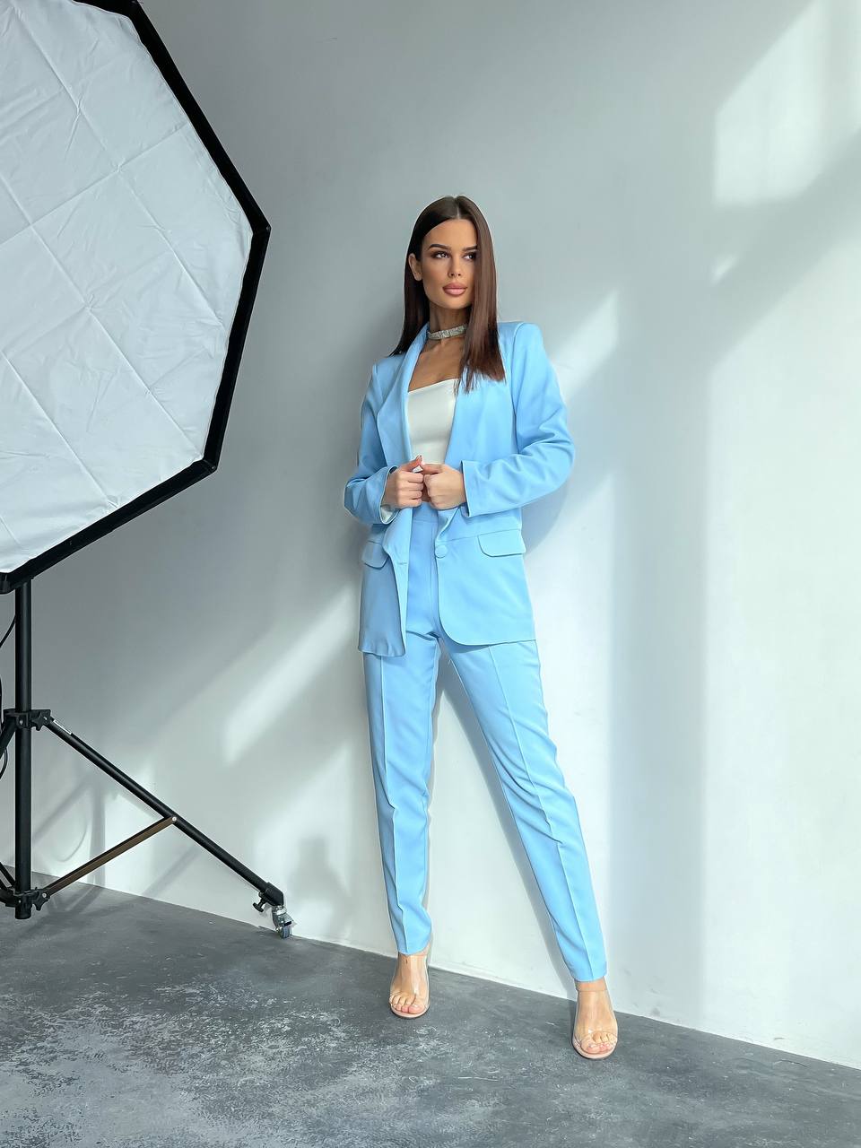 Person wearing a light blue suit standing in a studio setting with photography equipment.