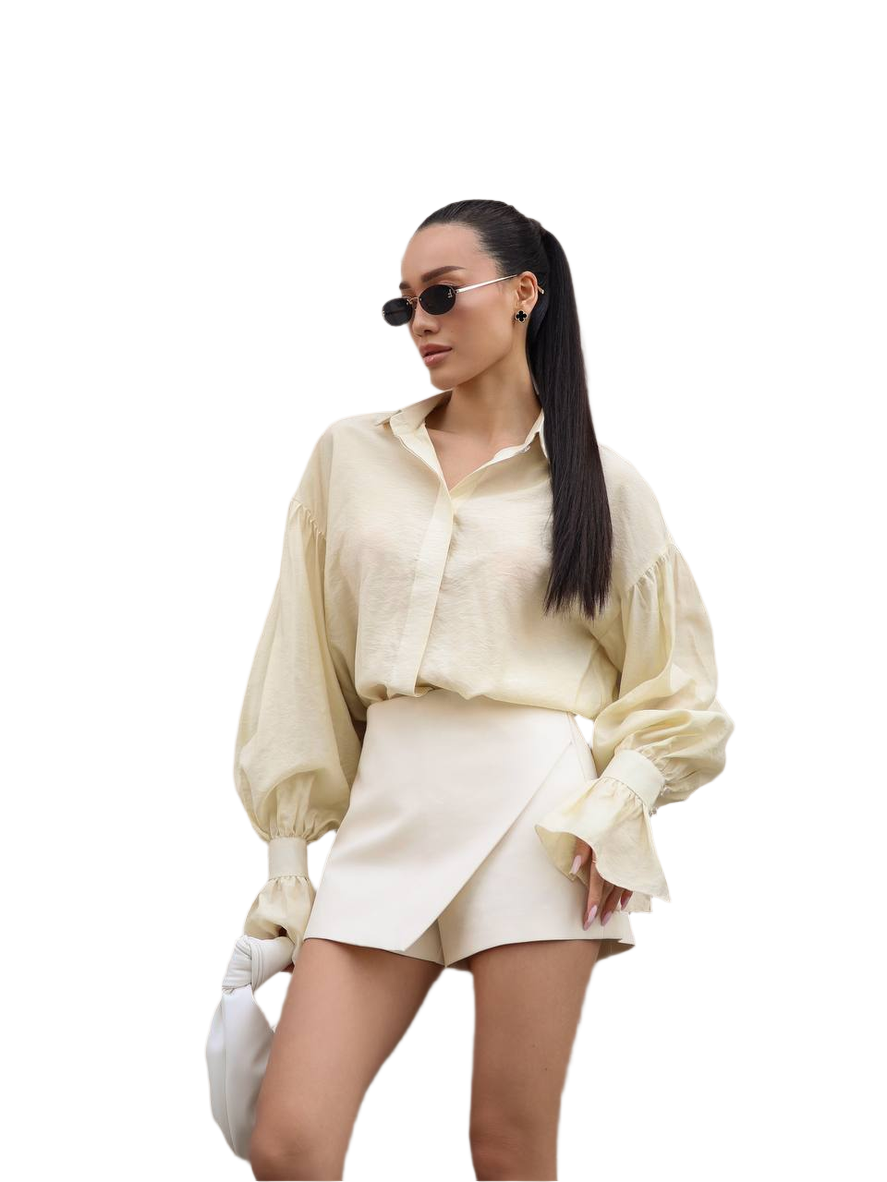 Person wearing a cream-colored outfit with sunglasses on a white background