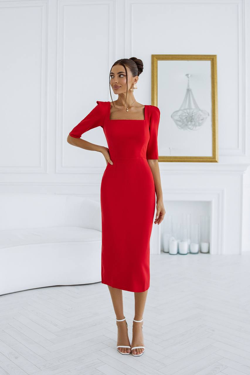 Woman wearing a red dress in a white room with a framed picture on the wall.