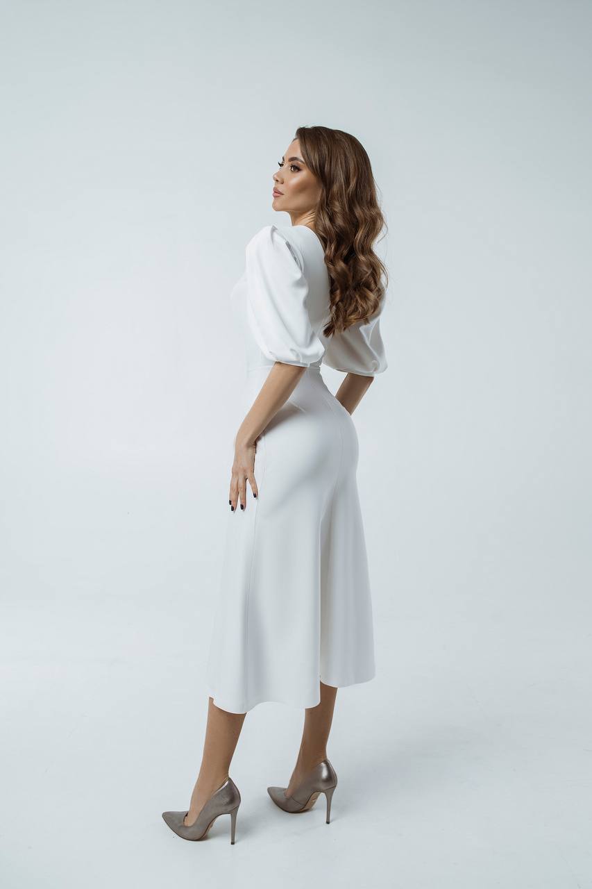 Woman wearing a white dress with puffed sleeves on a light gray background
