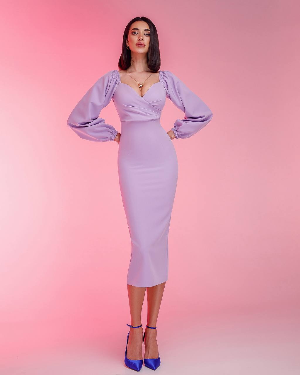 Woman wearing a lavender dress with long sleeves against a pink background