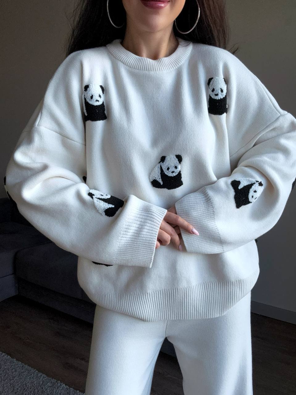 White sweater with panda designs worn by a person indoors.