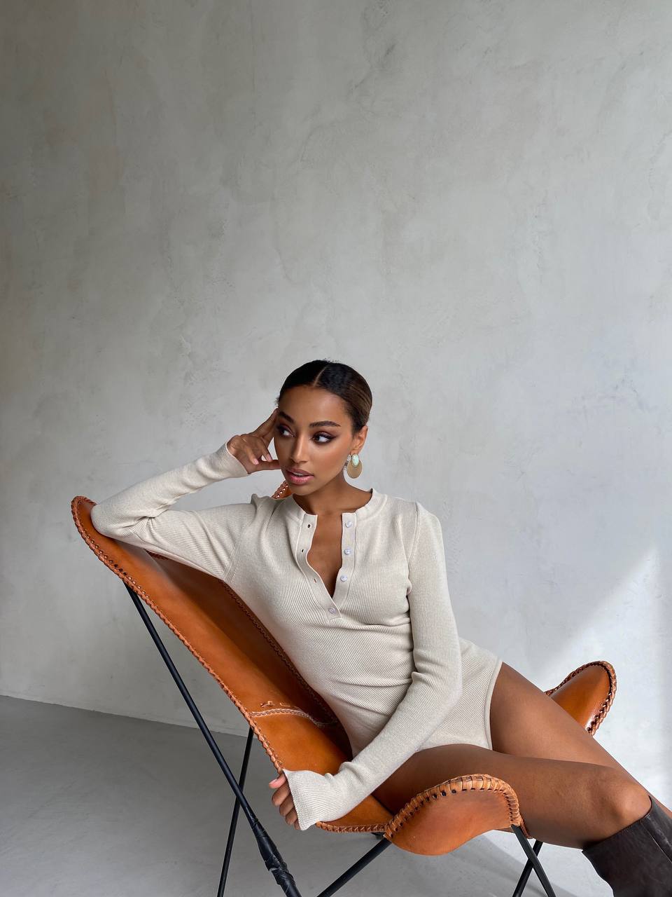 Woman sitting on a modern chair against a plain wall