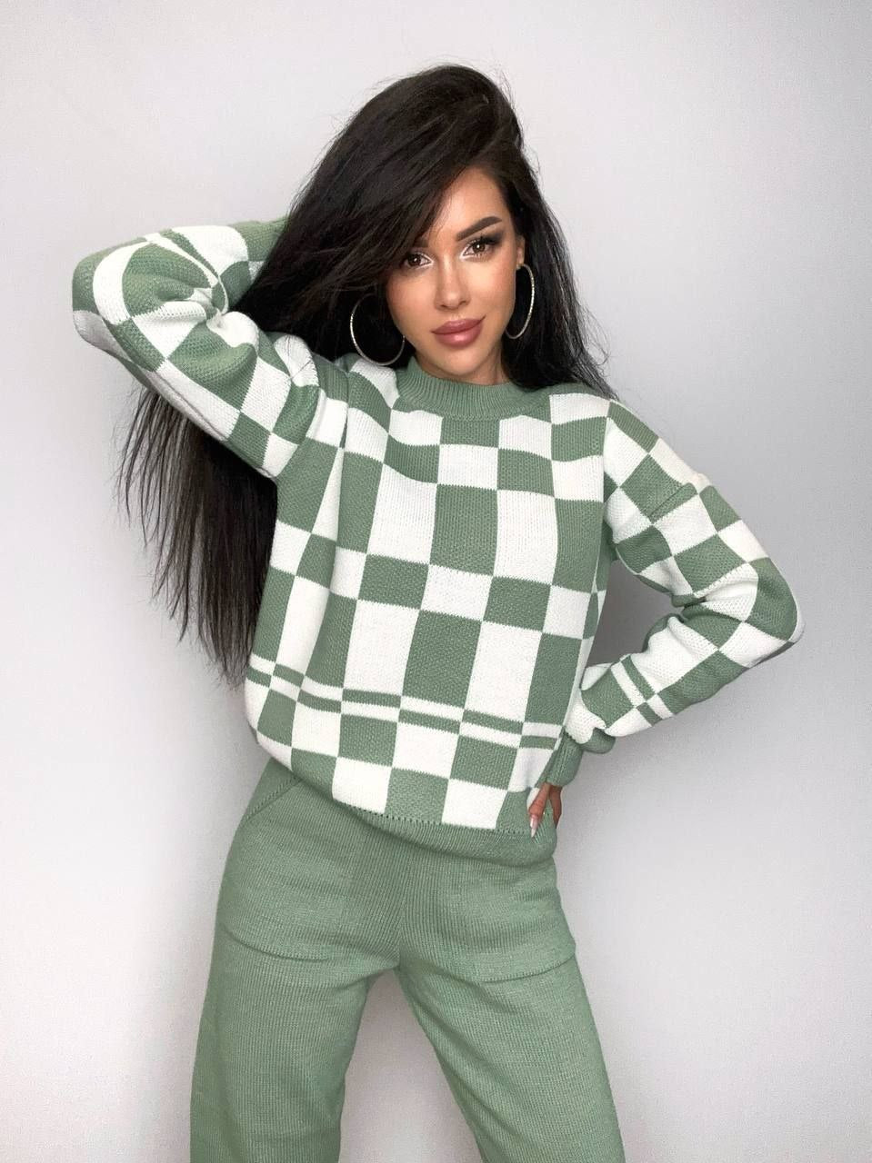 Woman wearing a green and white checkered sweater against a plain background