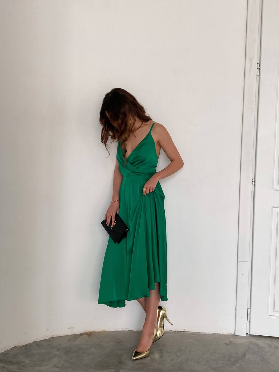 Woman wearing a green dress against a white wall