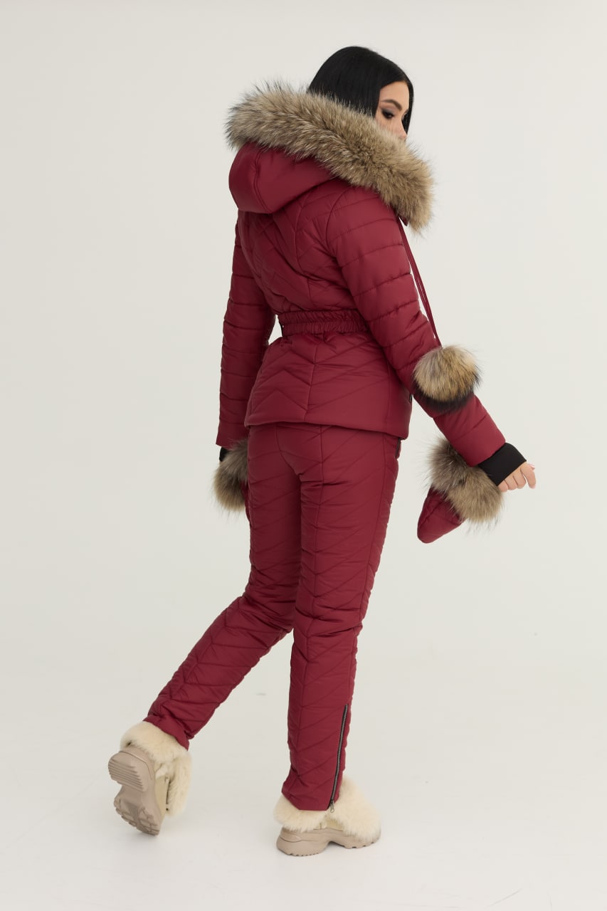 Person wearing a red winter coat with fur-lined hood and cuffs on a white background