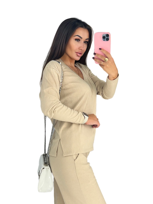 Woman in a beige suit taking a selfie with a pink phone on a white background