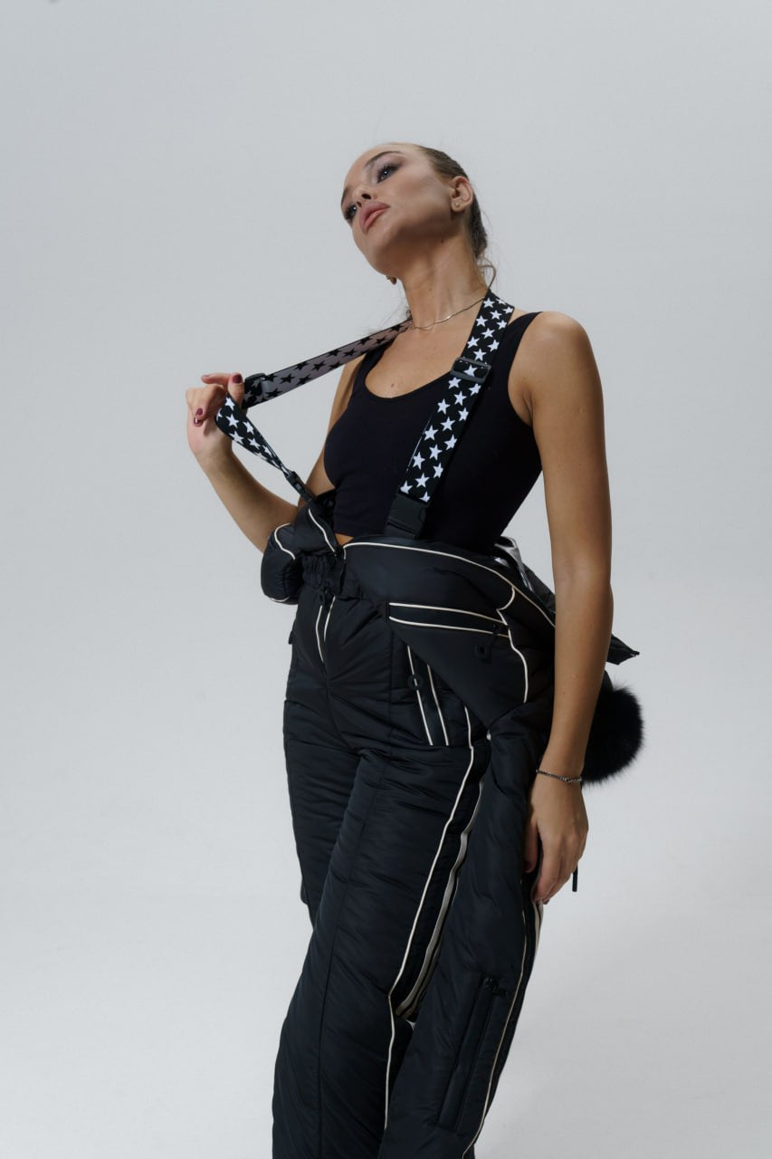 Woman wearing a black outfit with white accents against a plain background