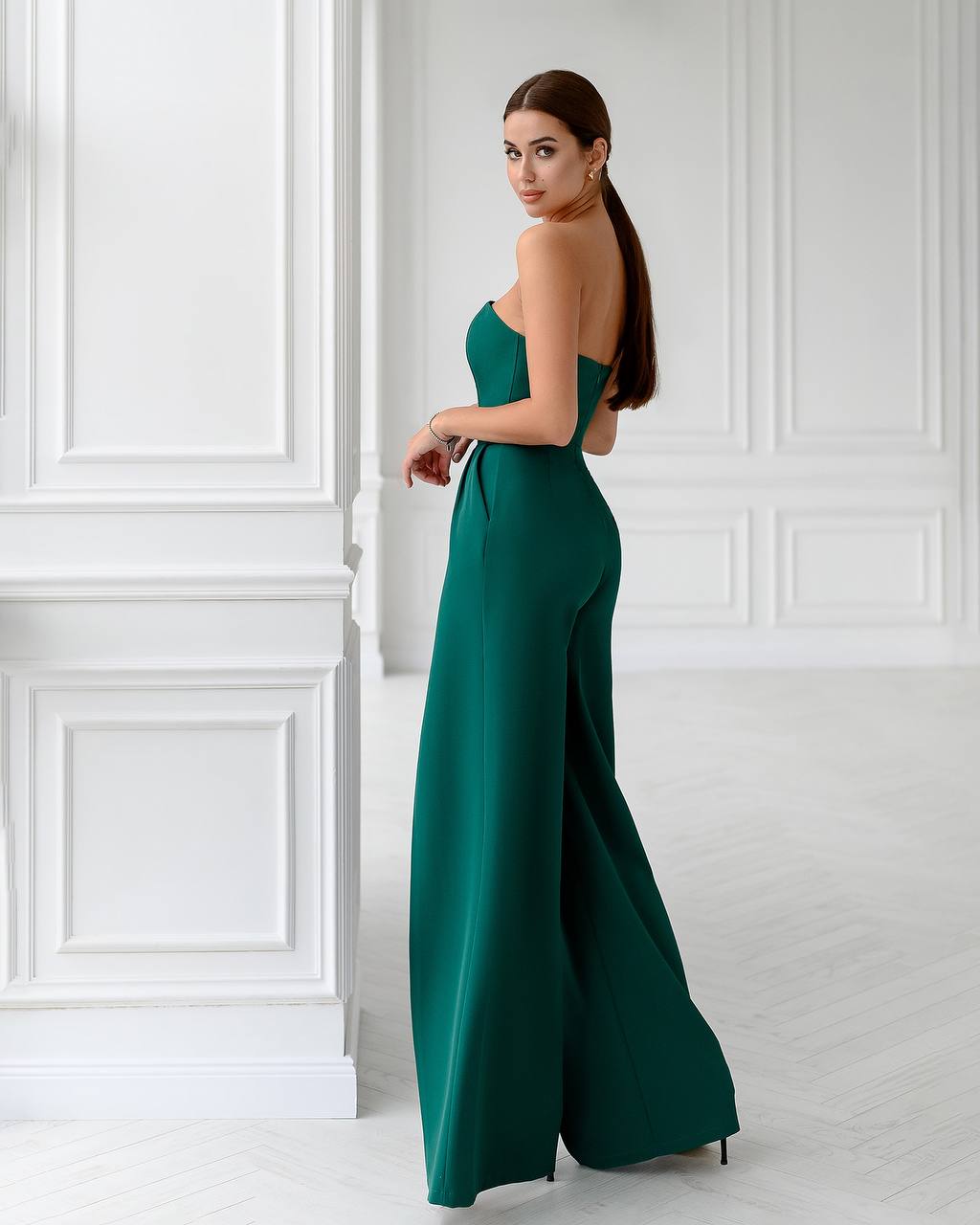 Woman wearing a green evening gown in a white room