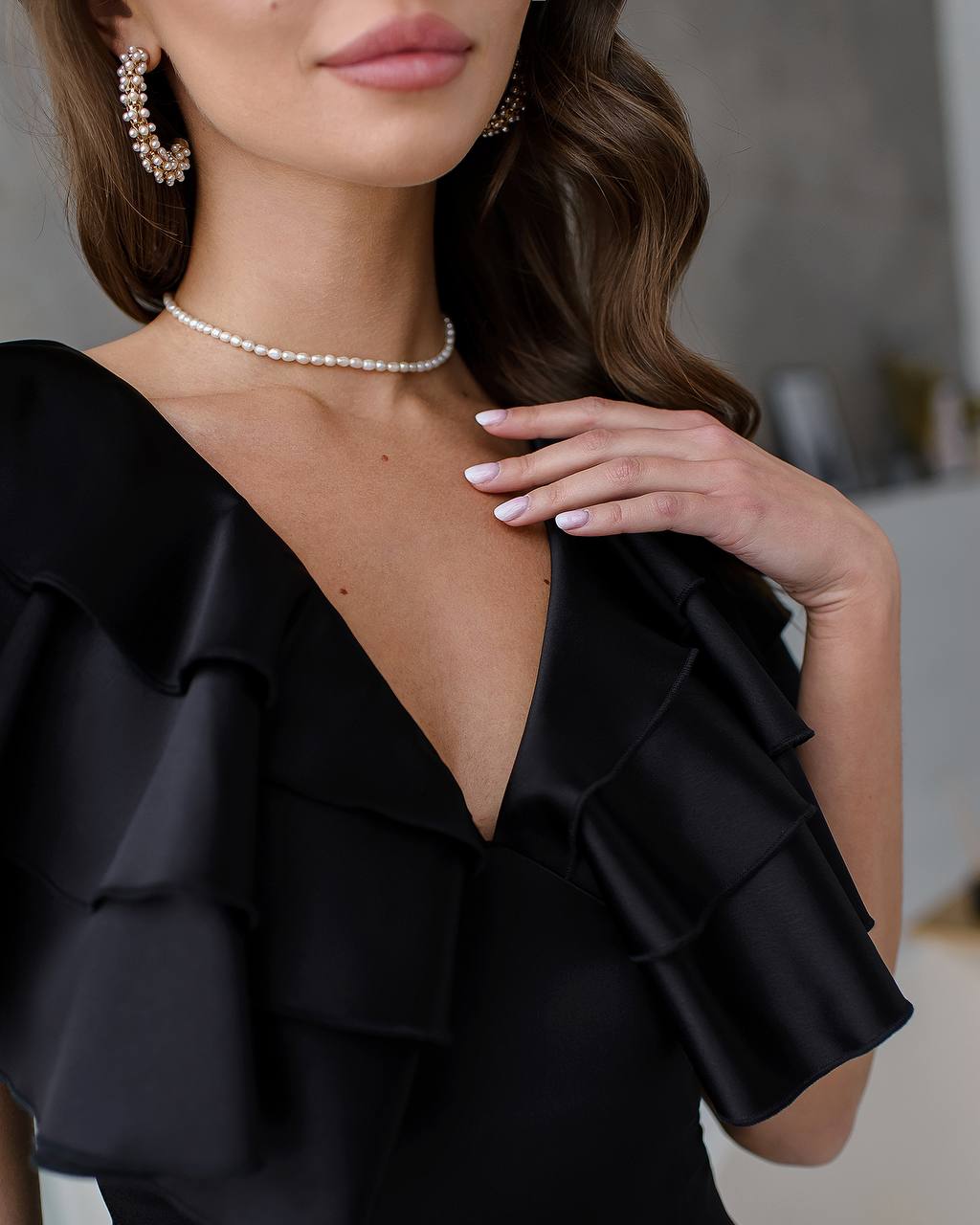 Black ruffled top worn by a model with a blurred background