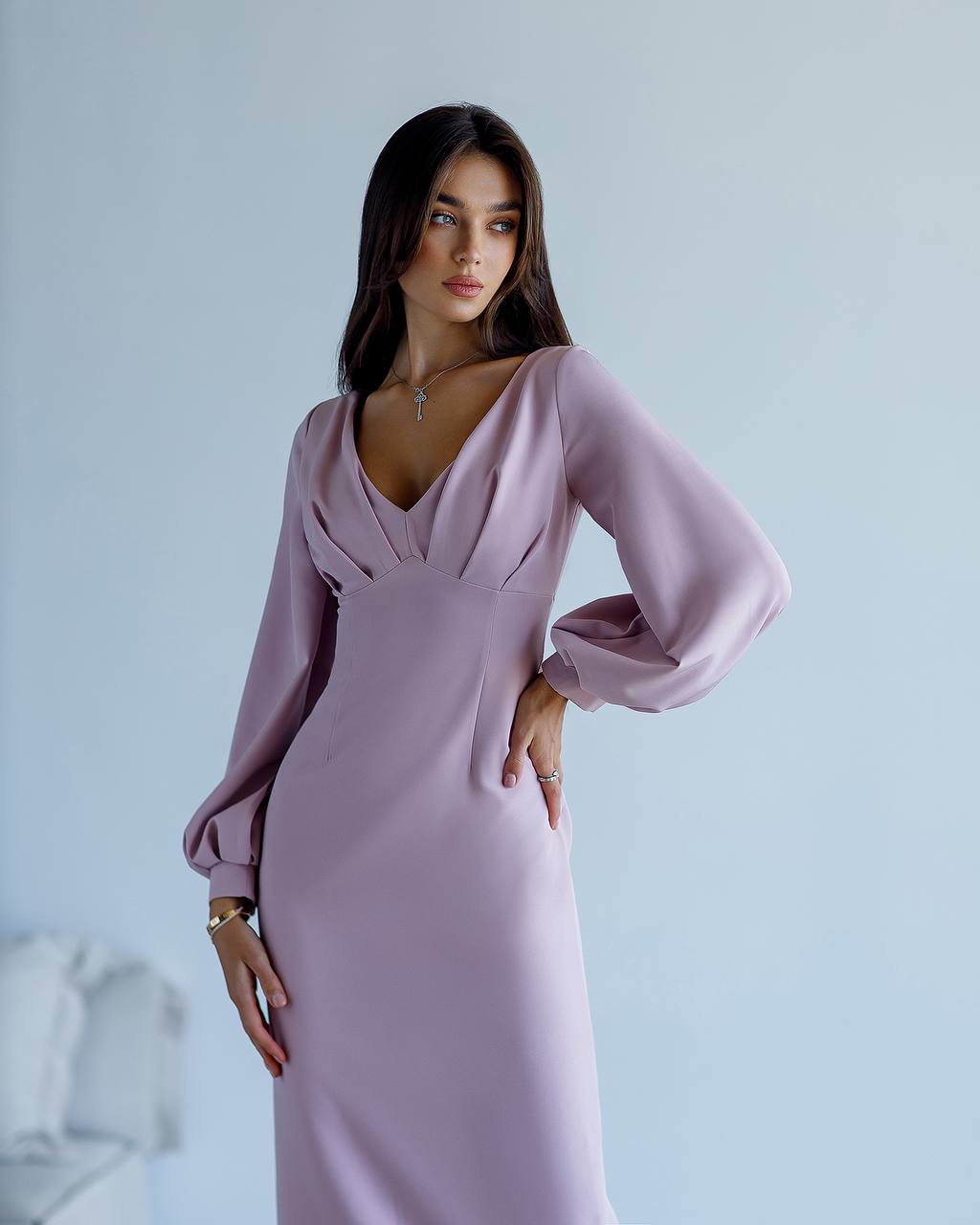 Woman wearing a light purple dress with long sleeves against a plain background