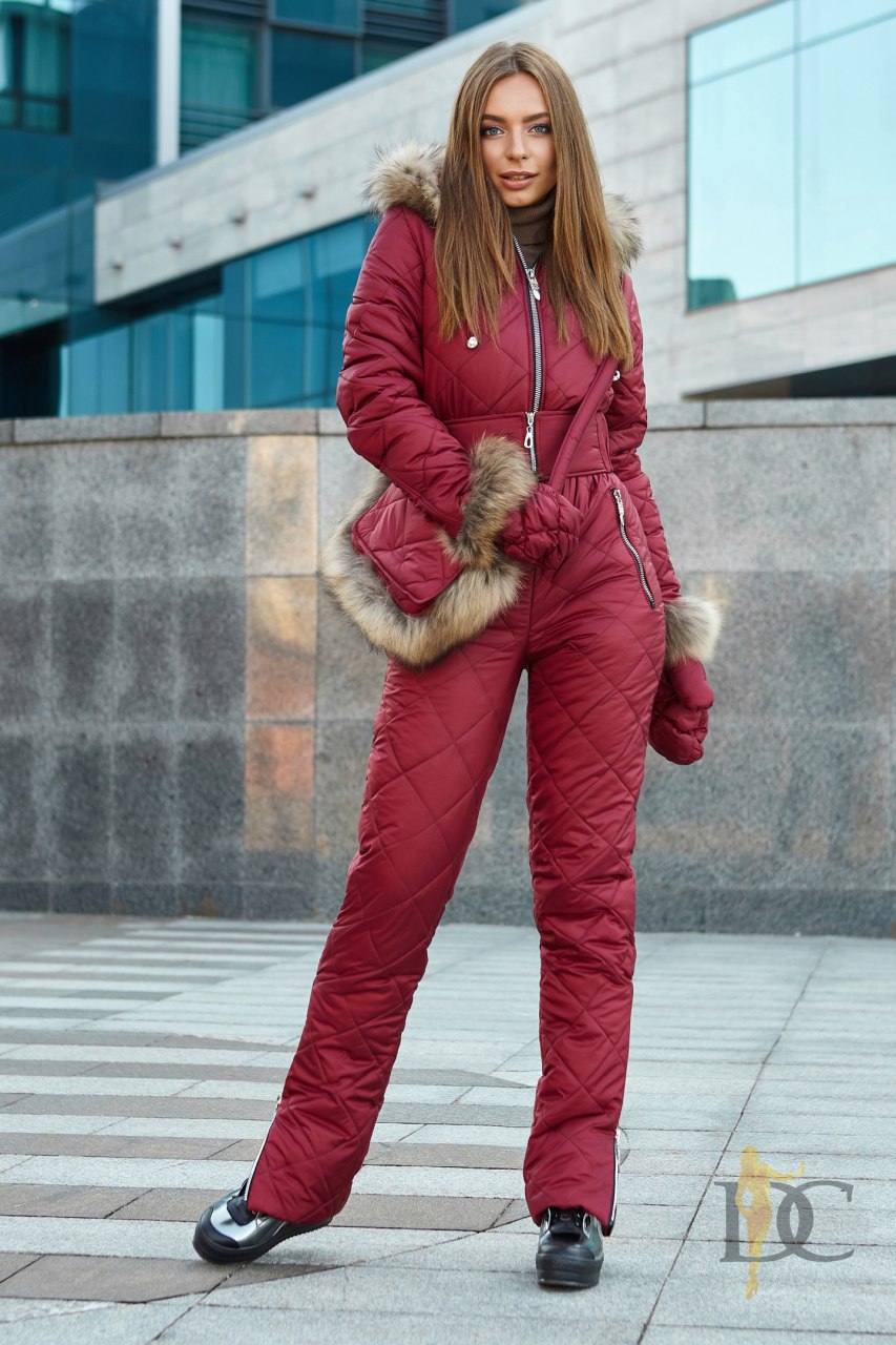 Woman wearing a red puffer jumpsuit with fur trim in an urban setting