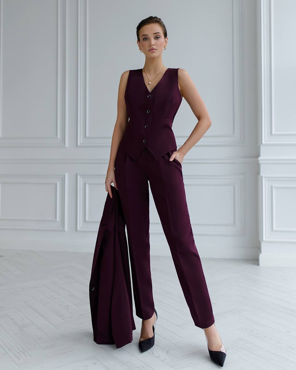 Woman wearing a burgundy suit with a white wall background