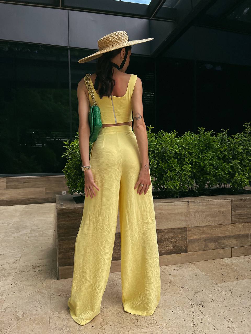 Woman in a yellow outfit with a wide-brimmed hat standing outdoors.