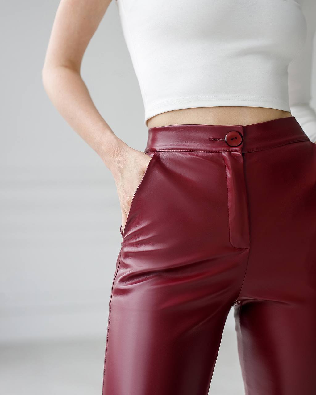 Maroon leather pants worn by a person on a plain background