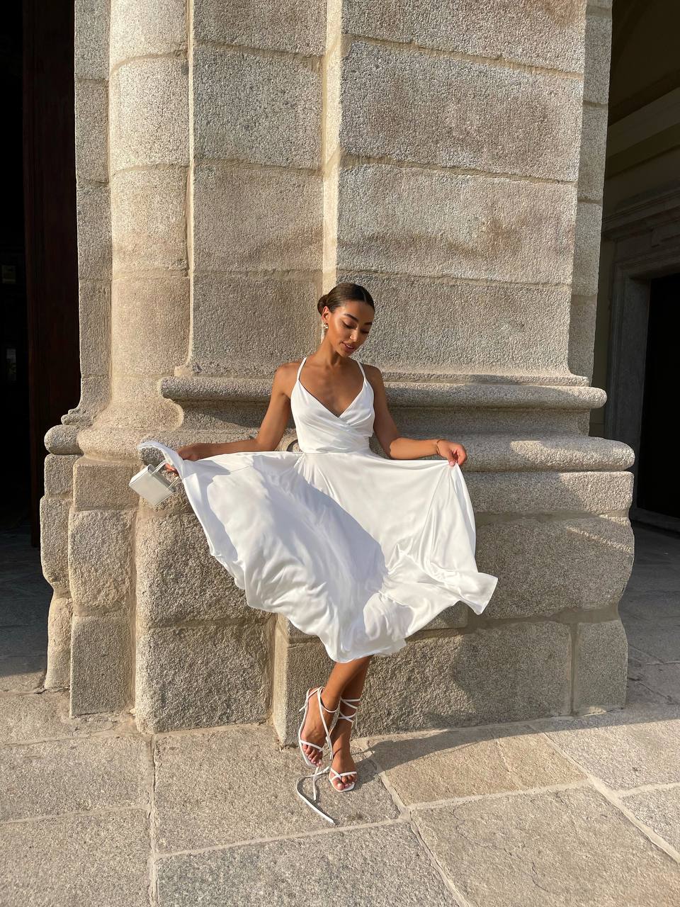 Woman in a white dress sitting on stone steps outdoors