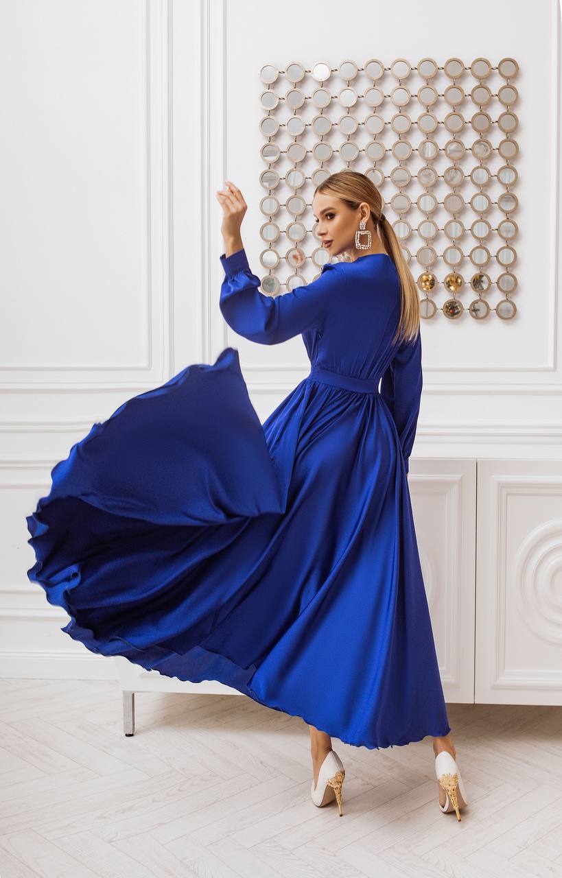 Woman in a blue dress twirling in a room with decorative wall art.