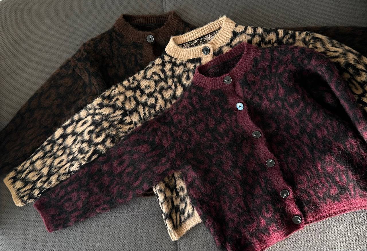 Two cardigans with leopard print sleeves on a gray surface