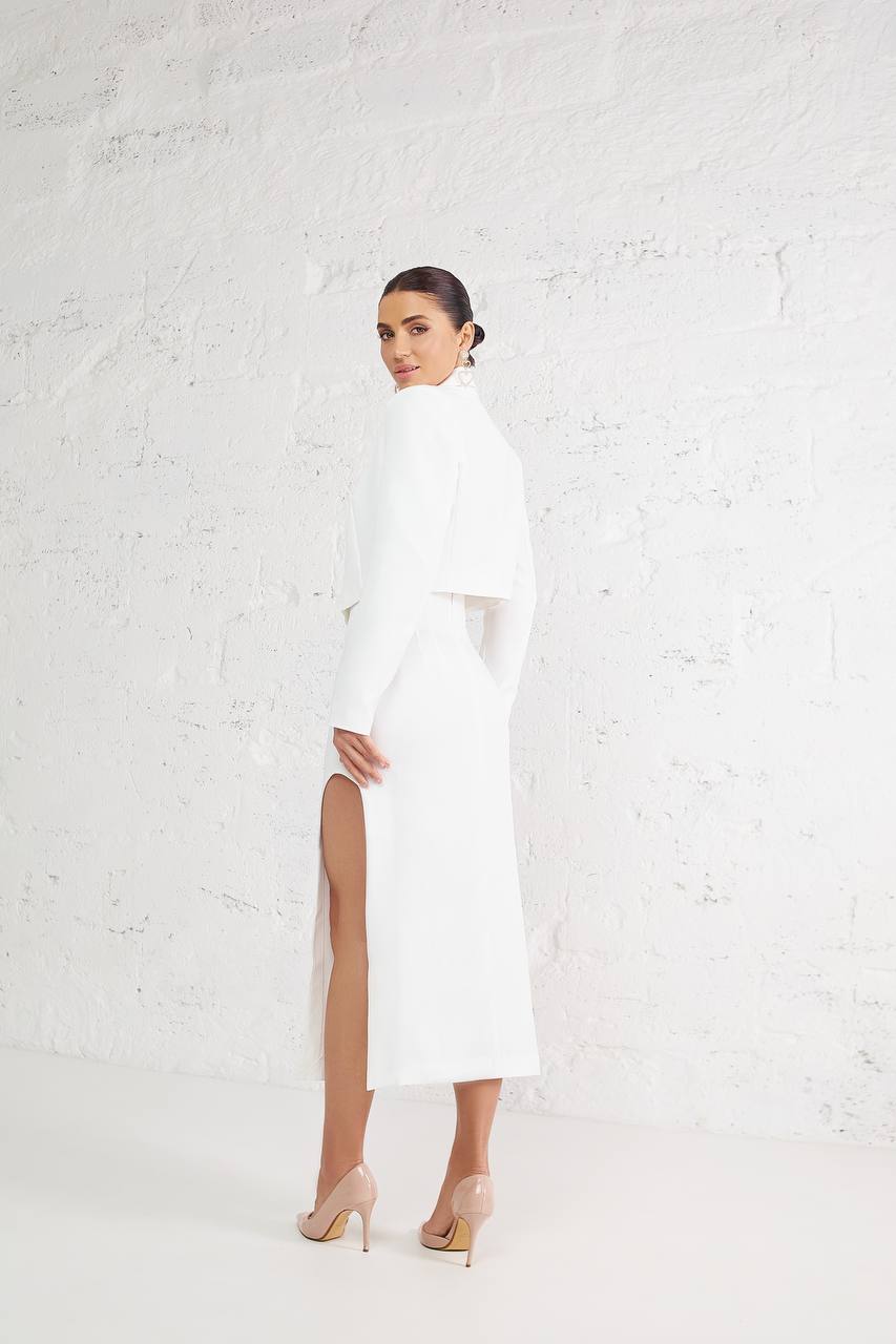 Woman wearing a white dress with a high slit on a light gray background