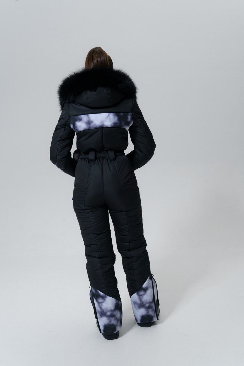Person wearing a black snowsuit with fur hood on a white background