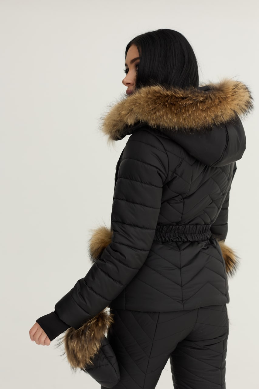Person wearing a black puffer jacket with fur trim on a plain background