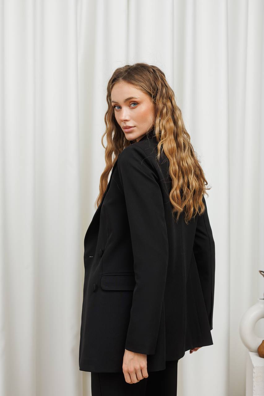 Woman wearing a black coat against a white curtain background