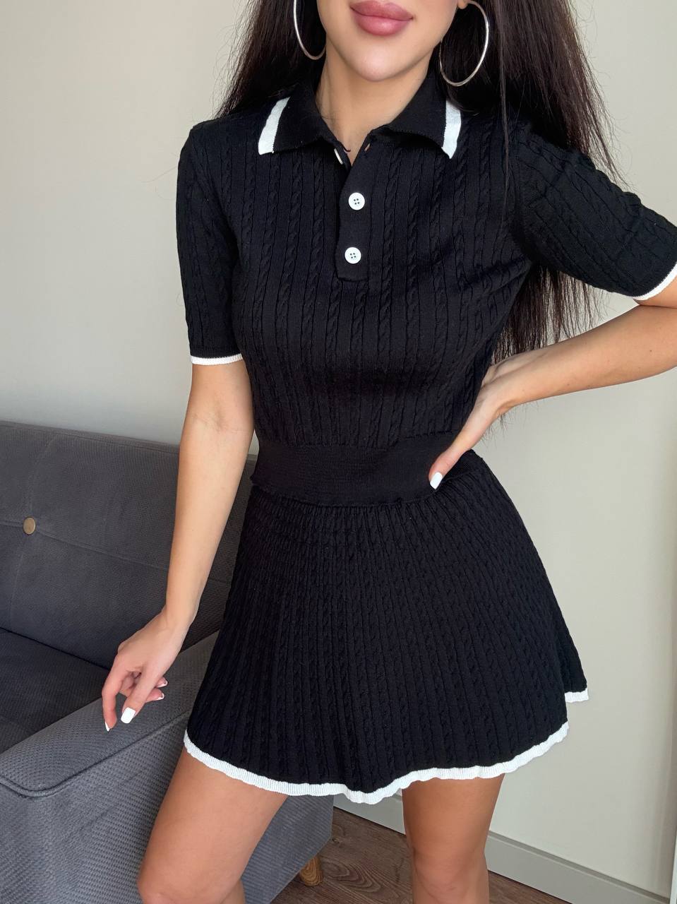 Woman wearing a black ribbed dress with white trim in an indoor setting.