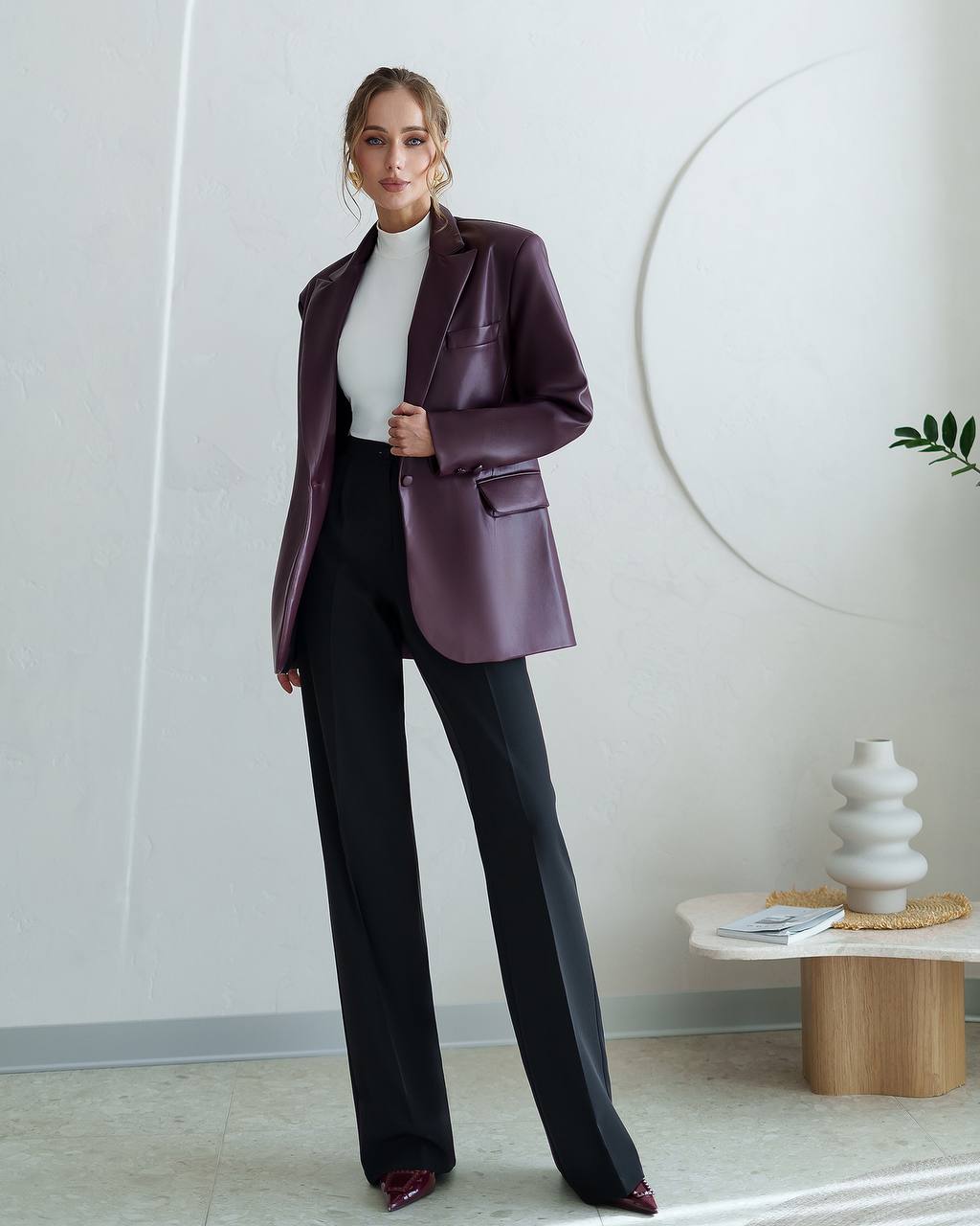 Woman wearing a purple blazer and black pants in an indoor setting.