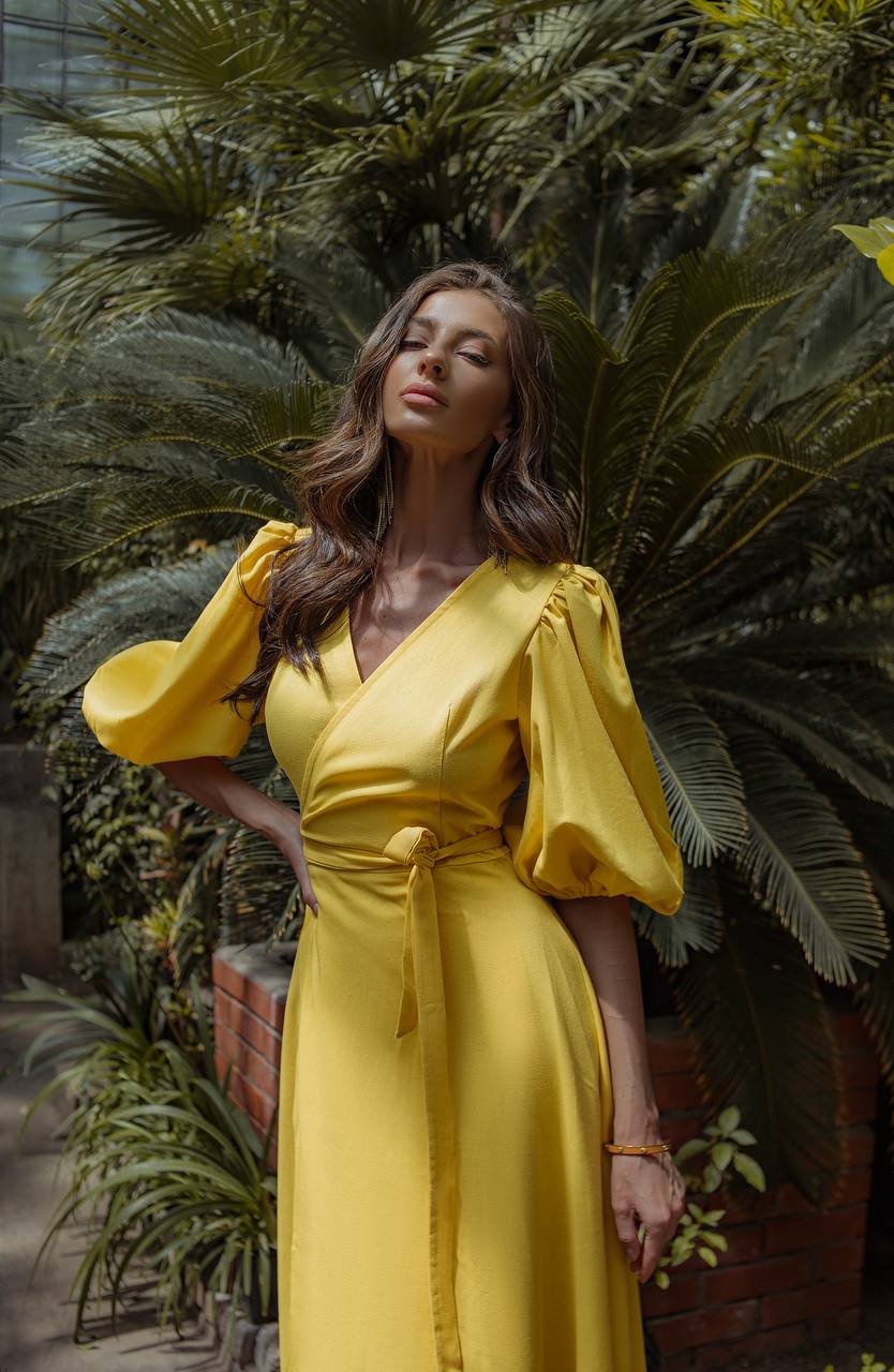 Woman in a yellow dress standing among tropical plants