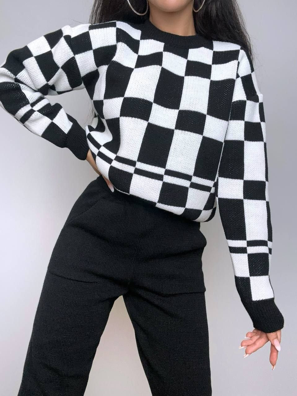 Person wearing a black and white checkered sweater against a plain background