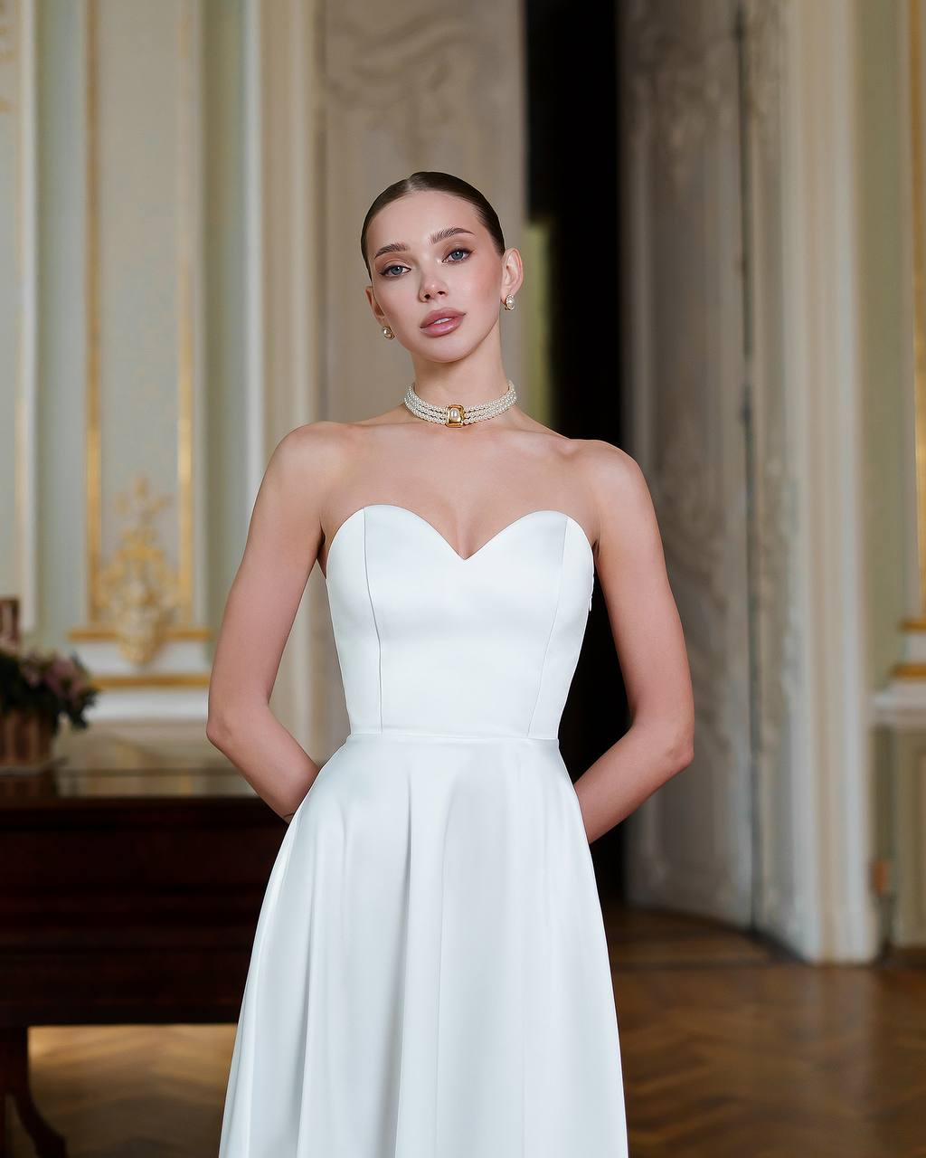 Woman wearing a strapless white wedding dress in an elegant indoor setting
