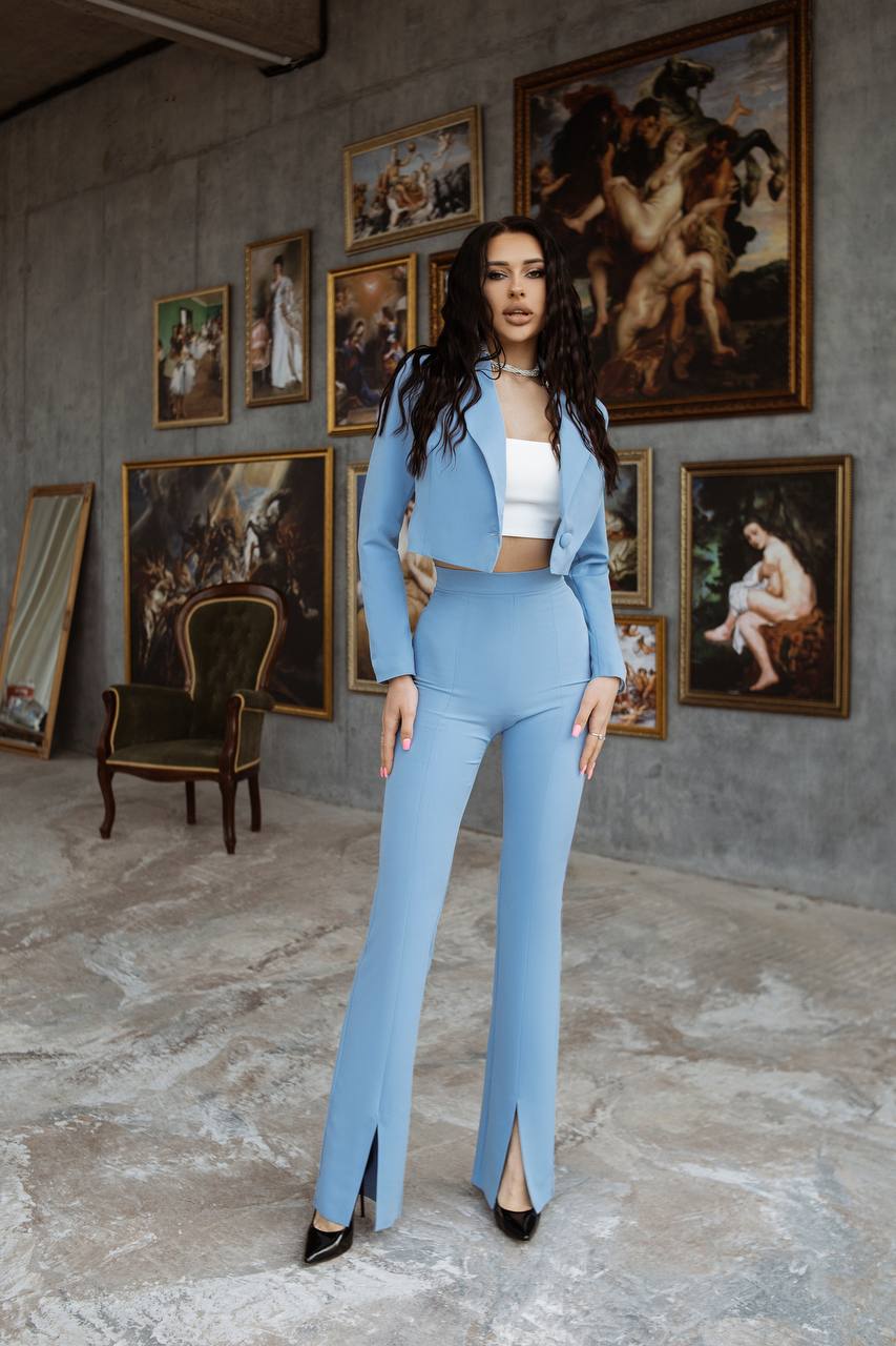 Woman in a light blue outfit standing in an art gallery with classical paintings on the wall.