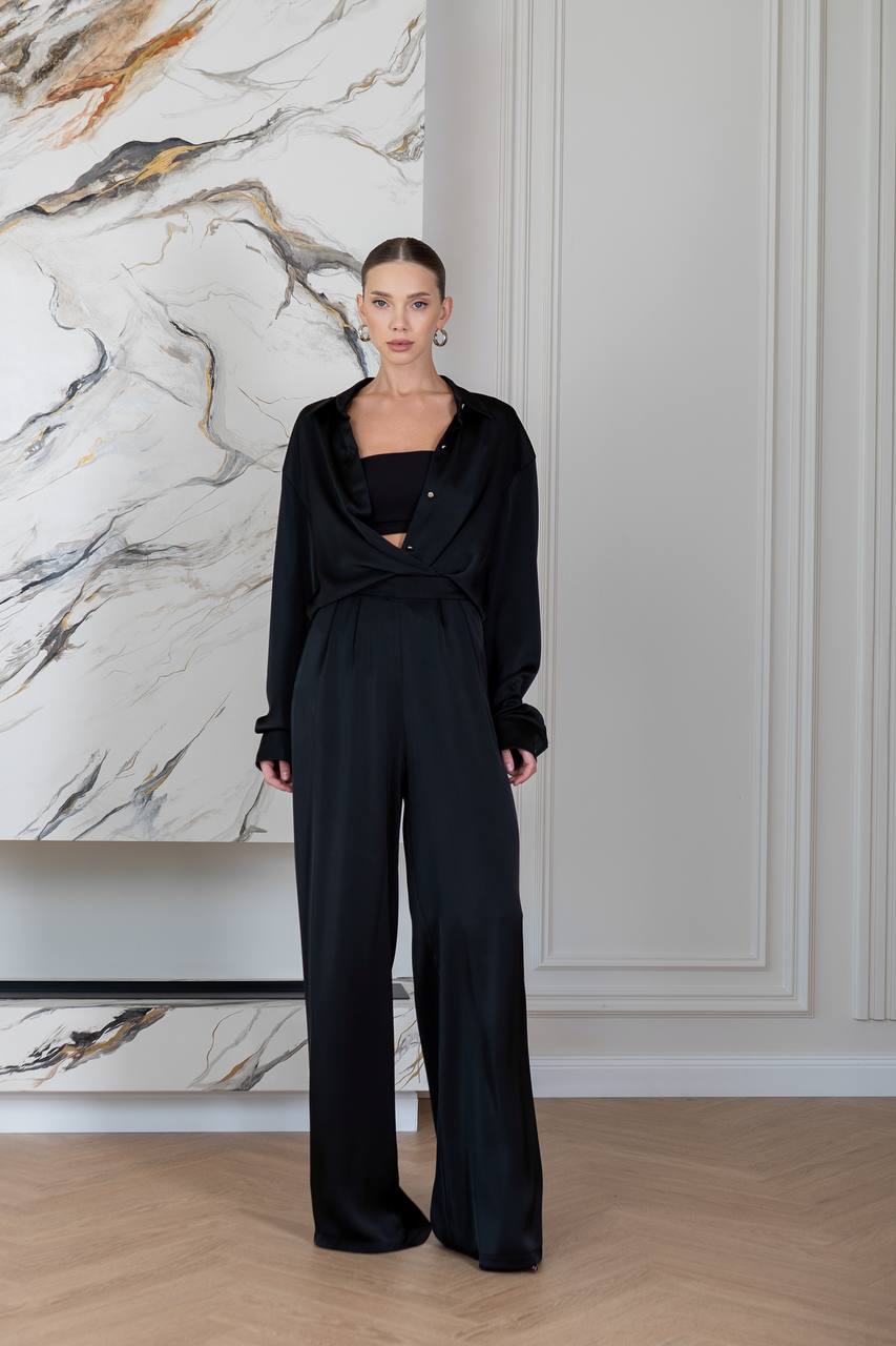 Woman wearing a black outfit standing in front of a marble wall.