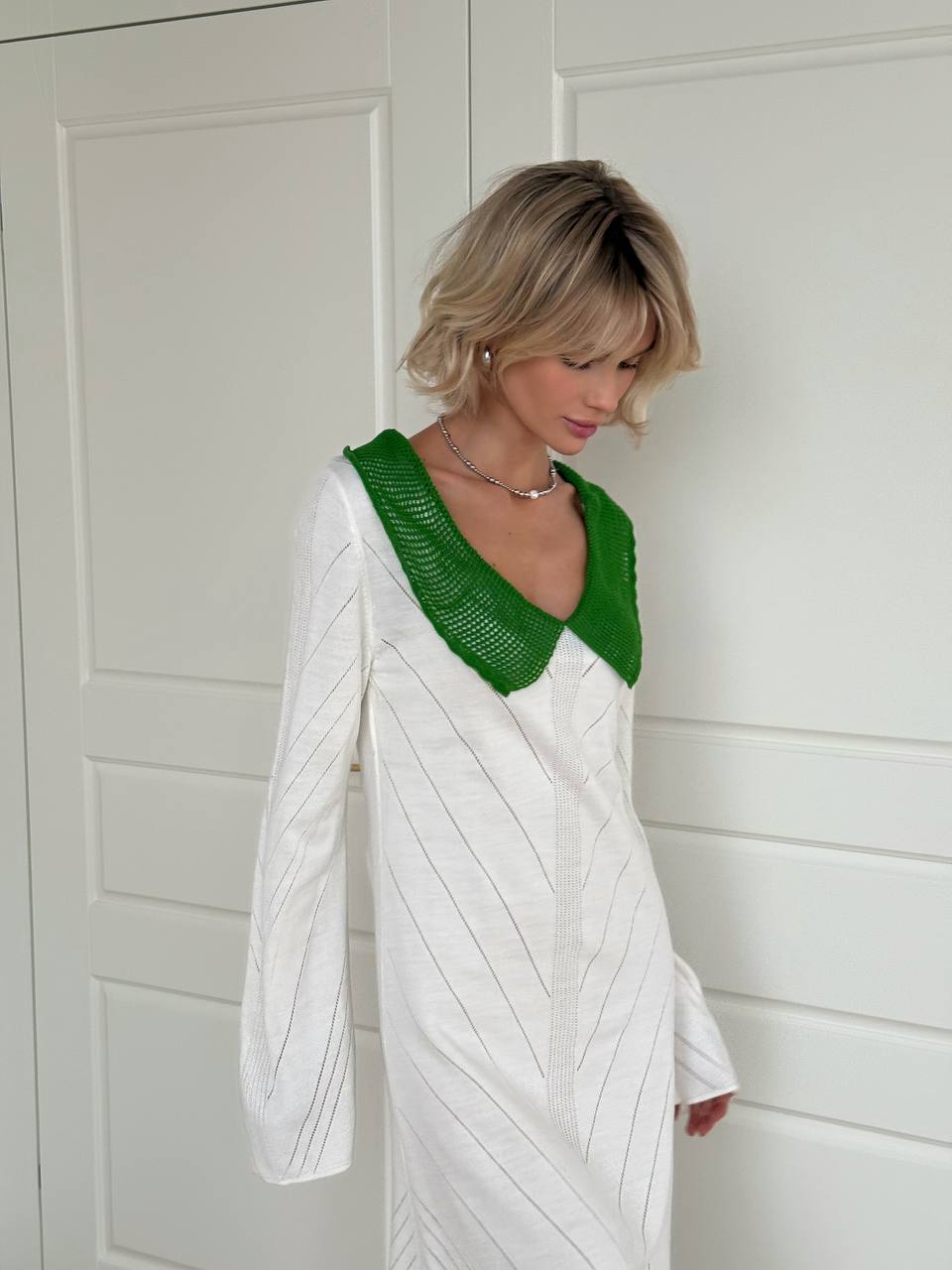 Woman wearing a white dress with green neckline against a white background