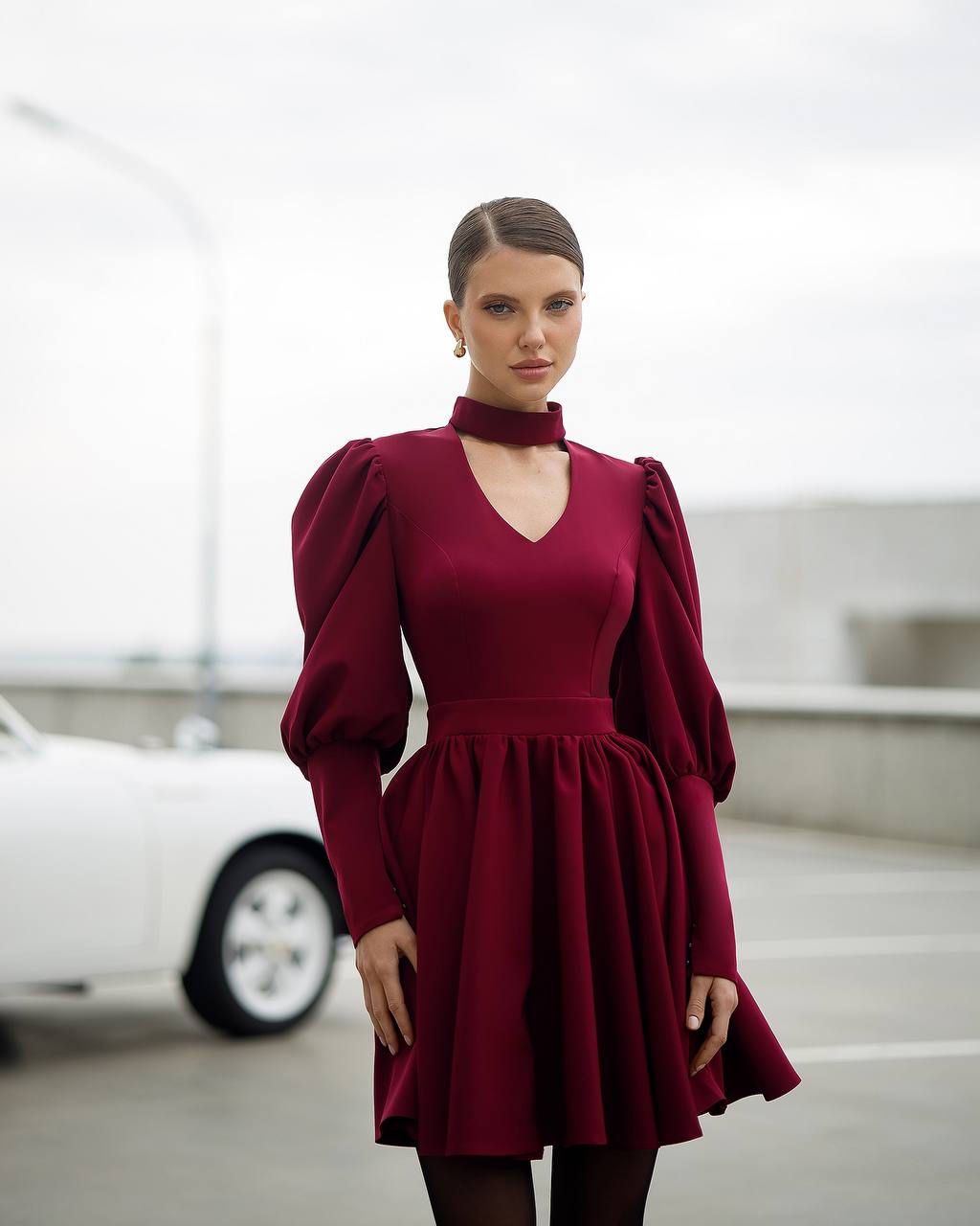 Woman wearing a burgundy dress with puffed sleeves in an indoor setting.