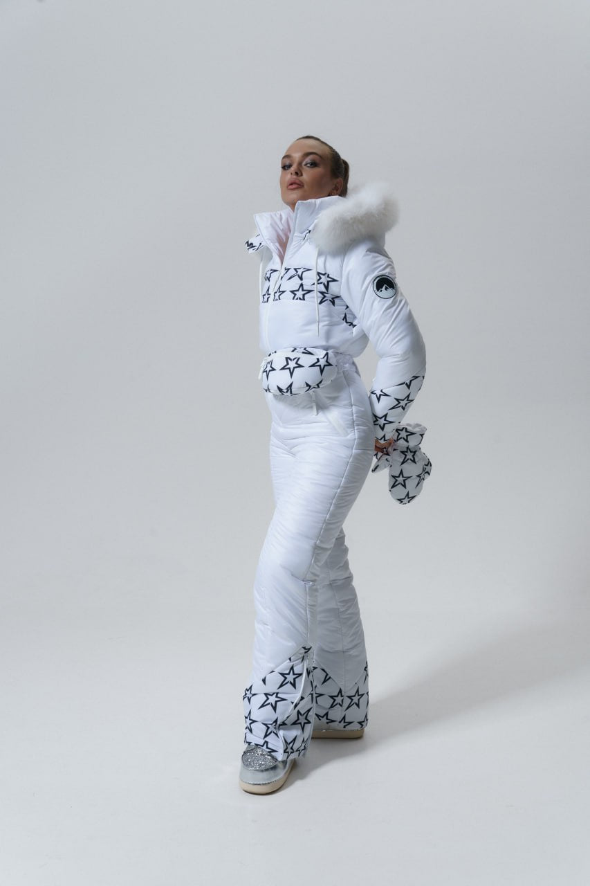 Person wearing a white snowsuit with black patterns on a plain background