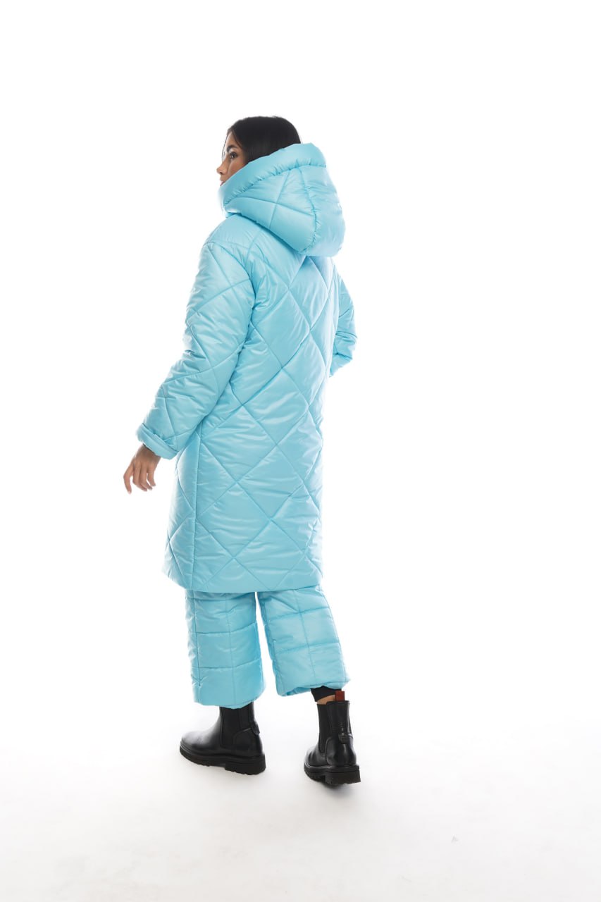 Person wearing a light blue quilted jacket and pants on a white background