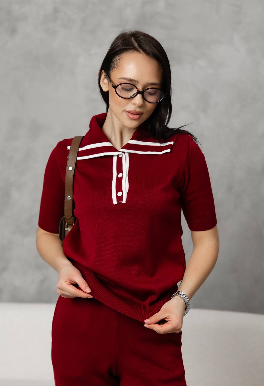 Woman wearing a red outfit with white accents against a gray background