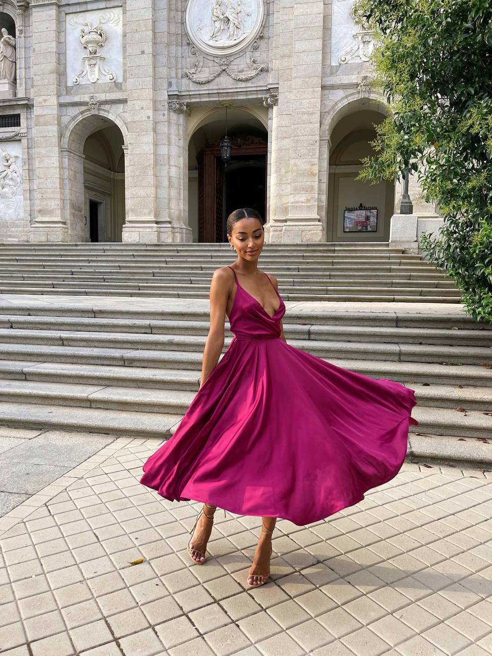 Woman in a pink dress standing on steps in front of an architectural building