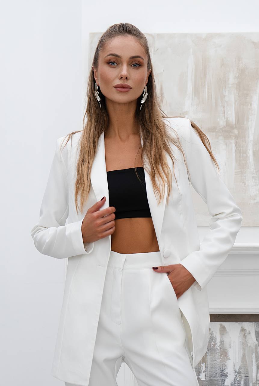 Woman wearing a white suit with a black top in an indoor setting