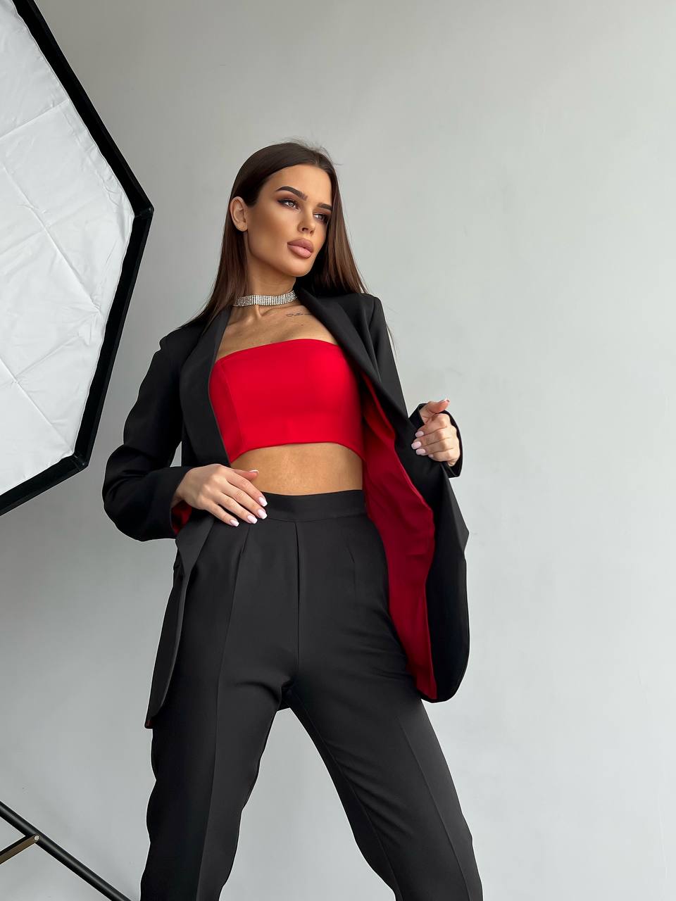 Woman wearing a red top and black blazer in a studio setting