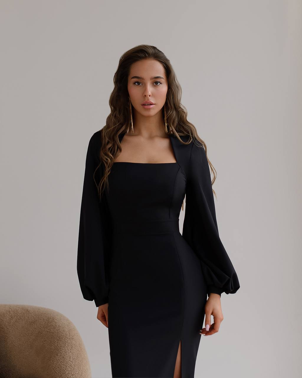 Woman wearing a black dress with long sleeves against a plain background