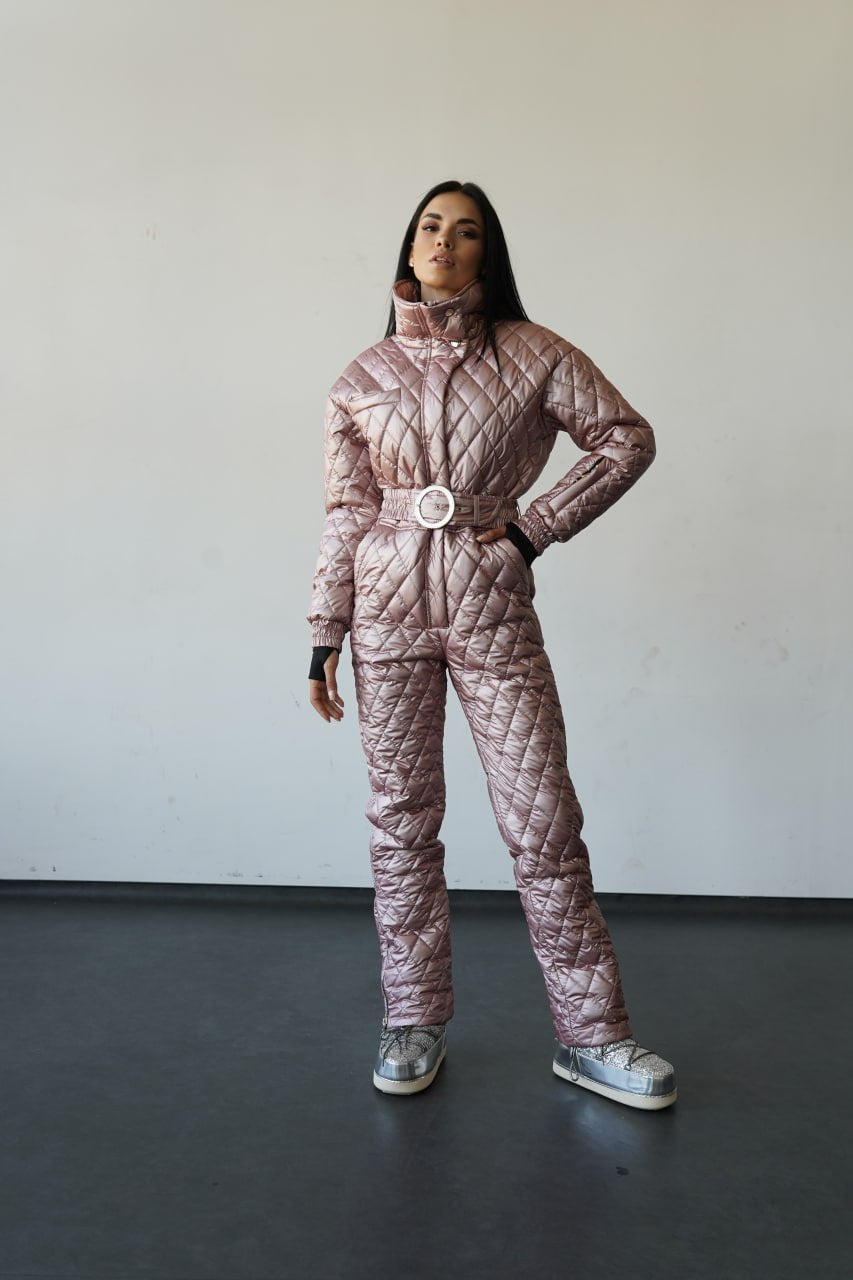 Person wearing a pink quilted jumpsuit with a white background