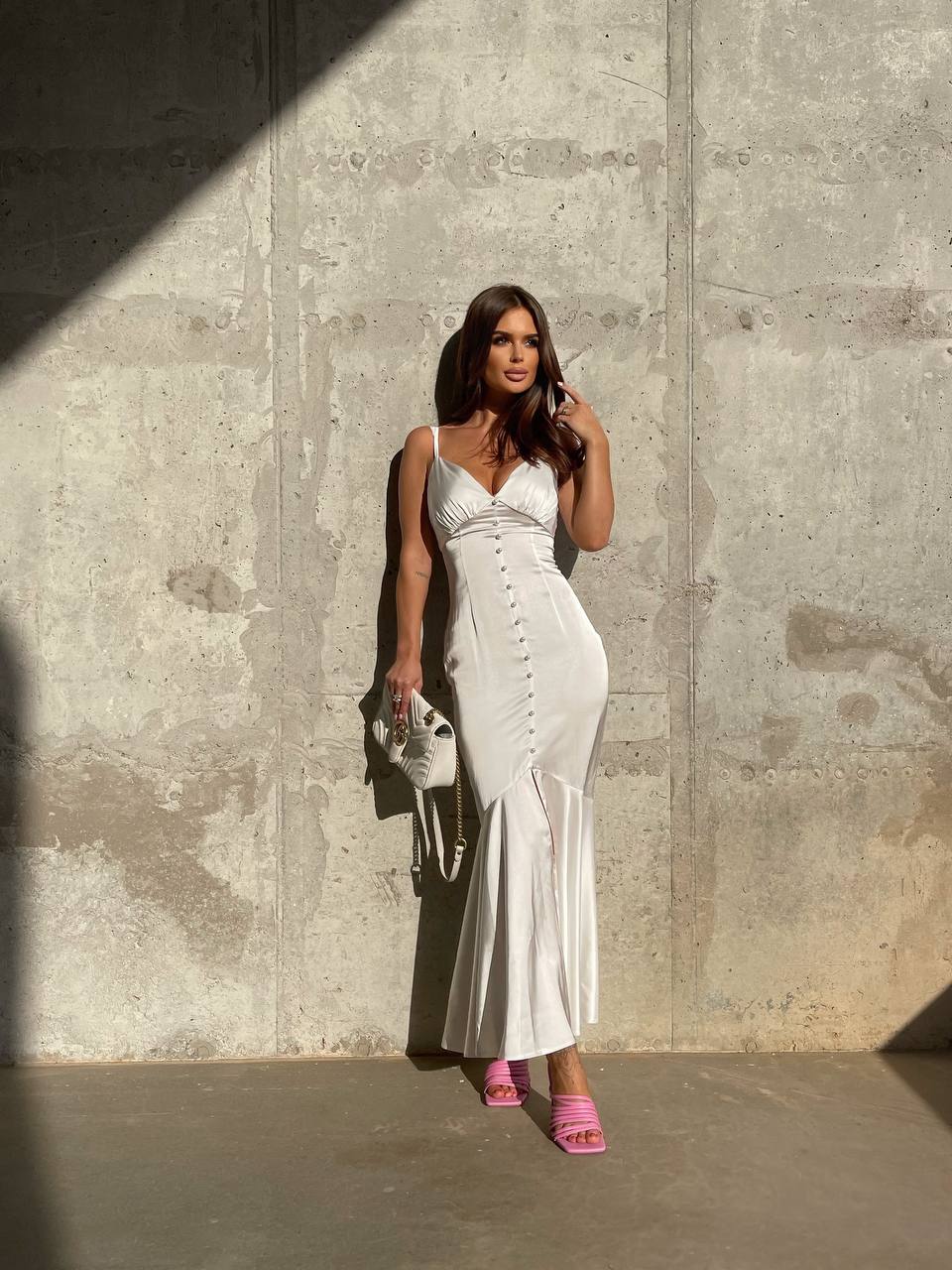 Woman in a white dress standing against a concrete wall